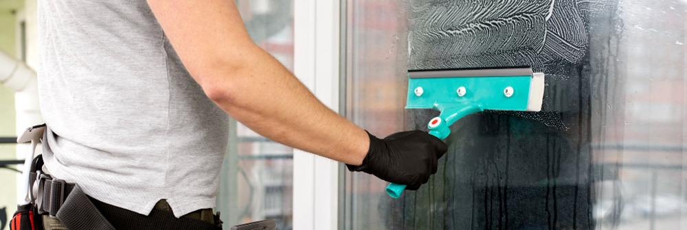 Reinigungskraft mit Abzieher säubert große Glasfläche – streifenfreie Fensterreinigung für klare Sicht